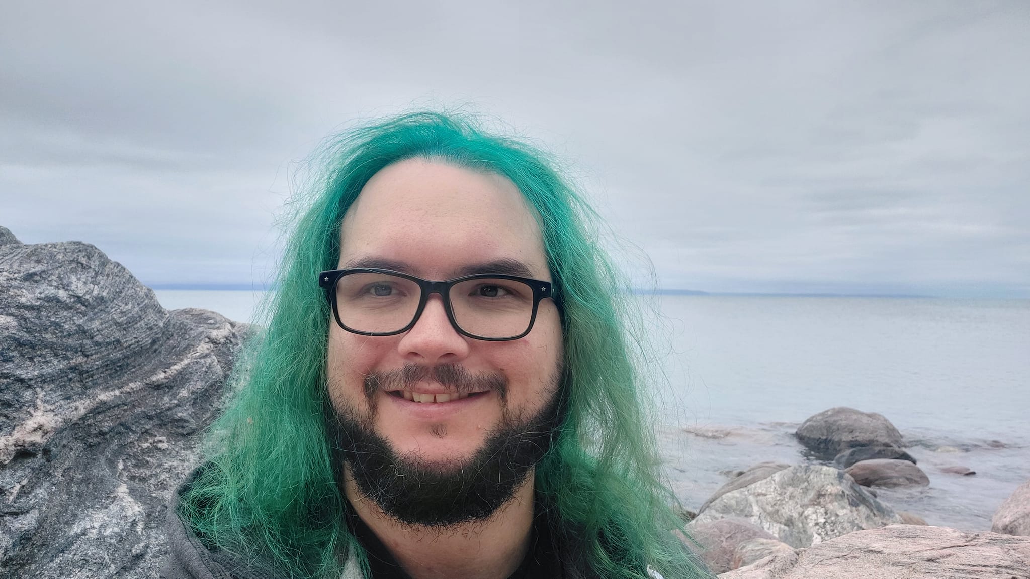 A man with green hair stands outside at a boulder breakwater, photo 15